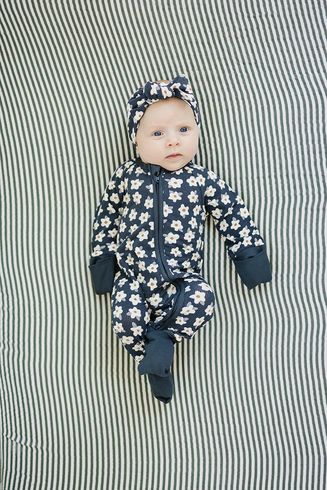 Navy baby onesie with white floral pattern on a white background. Mebie Baby