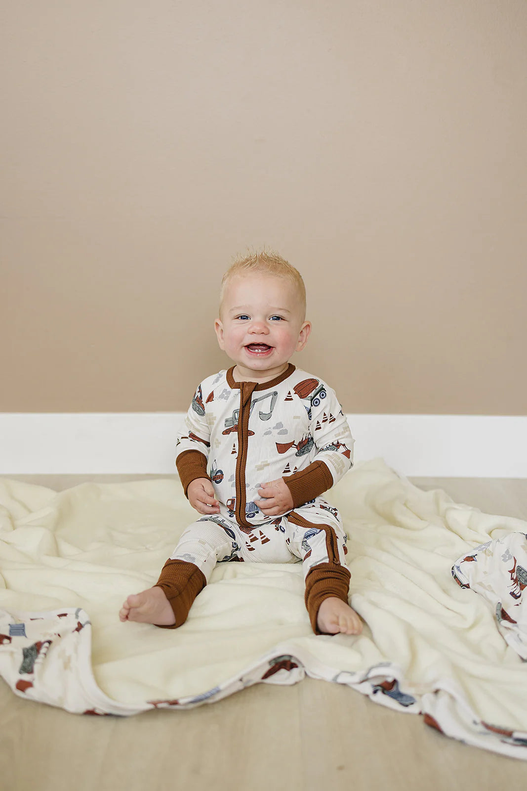Baby onesie with construction vehicle pattern on a white background. Mebie Baby
