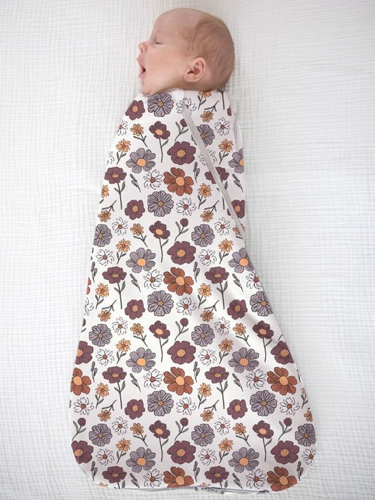 Baby swaddled in a floral patterned swaddle on a white background