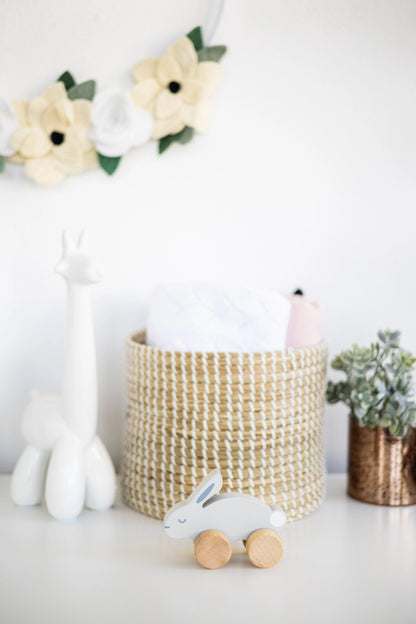 Children's room with toys, a woven basket, and decorative flowers on a white surface.